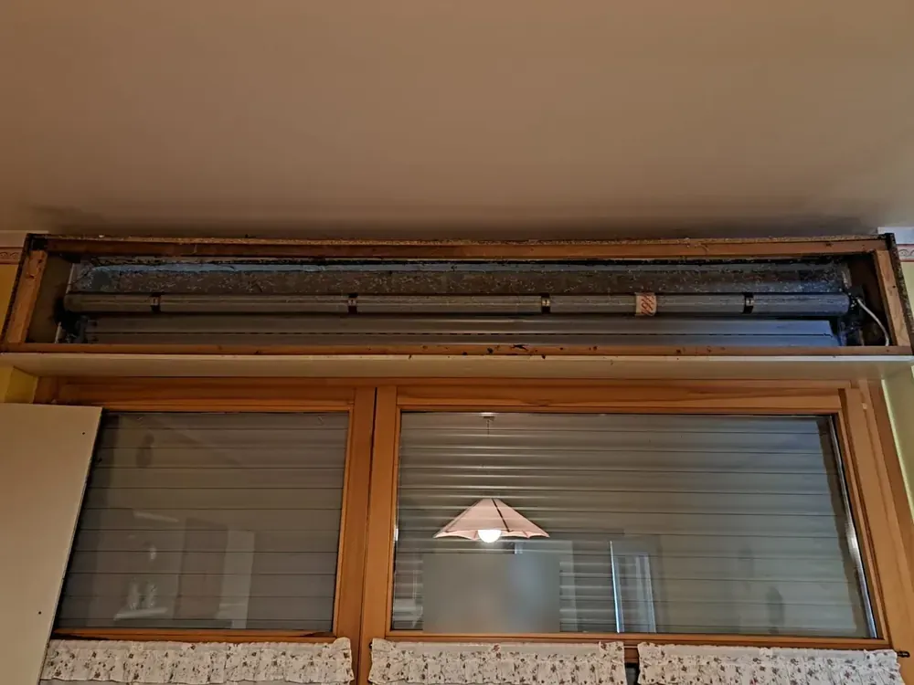 Motorizzazione tapparelle a Dozza: cassonetto aperto sopra una porta finestra con rullo e motore